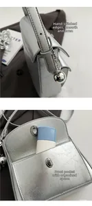 Detail of silver pleated leather crossbody bag with dual pockets and metal charm