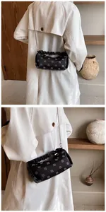 Detail of black pleated chain bag featuring white circular patterns and silver shoulder strap