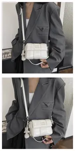 Detail of white woven crossbody bag with glossy finish and star-shaped charm accessory