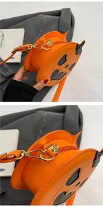 Detailed side view of pumpkin crossbody bag with black face and golden zipper accents