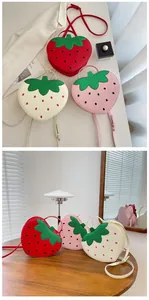 Close-up of strawberry-shaped crossbody bag featuring leafy decor and black polka dots