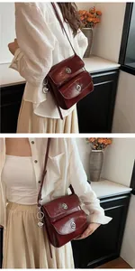 Detail of burgundy patent leather shoulder bag featuring silver metal clasps and dual pockets