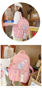 Detail of pink nylon school backpack featuring multiple transparent pockets and cute badges