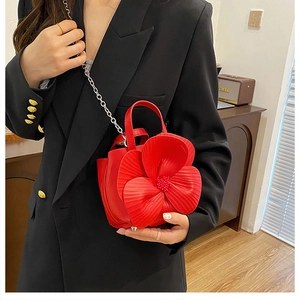 Detail of red 3D floral bucket bag featuring textured leather petals and silver chain strap
