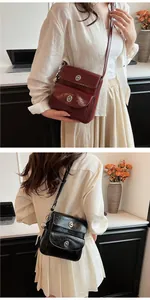 Detail of vintage glossy leather crossbody bag with round metal swivel lock and charm