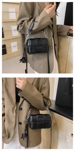 Detail of black woven square bag with silver star charm and chain strap texture