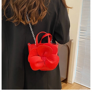 Detailed macro of red 3D floral petals with bead texture on minimalist leather handbag