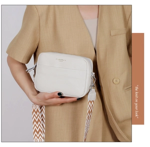 Detail of cream leather camera bag with ethnic style woven wide shoulder strap