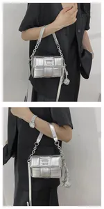 Close-up of silver woven square bag featuring metallic finish and spherical charm detail