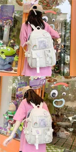 Detail view of cream canvas backpack featuring cute patches and clear PVC pockets