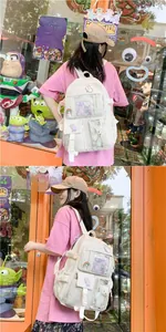 Detailed view of white nylon campus backpack with clear pocket and decorative badges