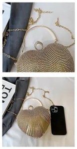 Detail of heart-shaped gold evening bag with rhinestones, metal ring handle and chain