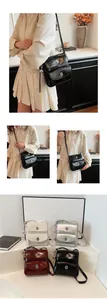Detail of glossy crossbody bags with double flaps and metallic circular logo accents