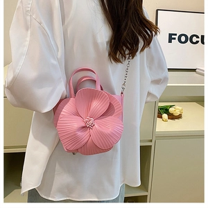 Pink petal-shaped handbag with 3D texture and metal chain strap shown on shoulder