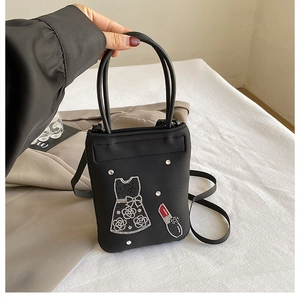 Detail of a black nylon crossbody bag with sparkling rhinestone lipstick and dress motifs