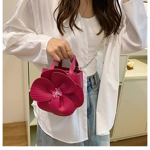 Detail of trendy rose red PU handbag featuring a large 3D floral design and chain strap