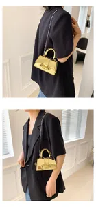 Mini gold mirror handbag with bead chain strap shown on black blazer for scale