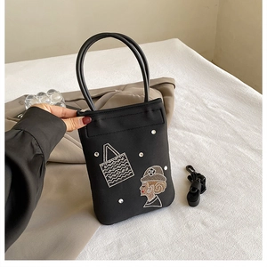 Detail of black nylon crossbody bag with rhinestone lady figure and sturdy round handles