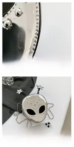 Detail of alien-shaped silver mirror crossbody bag with star antennae and metal chain
