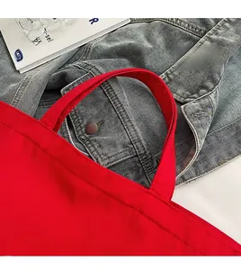 Détail des poignées larges renforcées d'un sac cabas en toile rouge aux coutures nettes