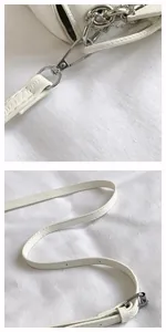 Detailed shot of silver metal hooks and white leather strap on a chic woven square bag