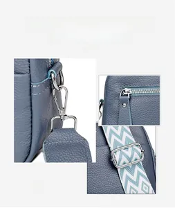 Detail of silver hardware hooks and blue-white geometric jacquard strap on leather bag
