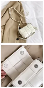 Close-up of white woven crossbody bag with metallic magnetic buckle and leather texture