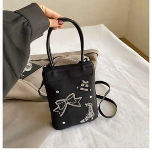 Detail of black nylon mini bag with rhinestone bow and boot patches on a blazer