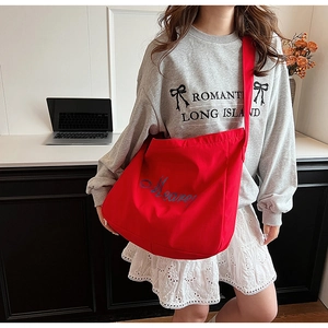Détail du sac cabas rouge en toile avec broderie bleue et large bandoulière réglable