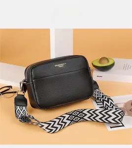 Detail of black pebbled leather crossbody bag with geometric woven strap and gold logo