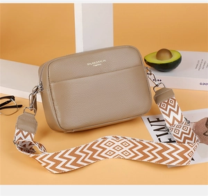 Detail of warm khaki leather camera bag with stylish wide geometric woven strap