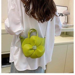 Close-up of a bright green 3D flower-shaped crossbody bag with pearl core and metal chain
