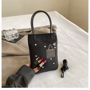 Detail of black nylon mini crossbody bag with rhinestone lipstick and handbag patterns