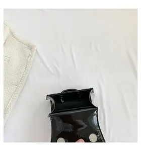 Detail view of mini black glossy patent leather bag with magnetic buckle closure