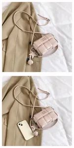 Pink woven square crossbody bag with star charms and phone size comparison view