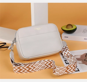 Close-up of white pebble leather camera bag with ethnic geometric wide shoulder strap
