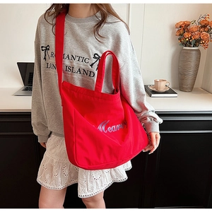 Photo lifestyle d'un grand sac cabas rouge en toile avec bandoulière et motif bleu