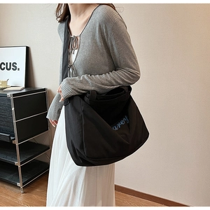 Détail de la broderie bleue sur un grand sac cabas en toile noire avec bandoulière chic