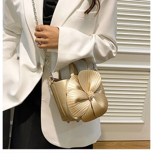 Detailed view of a golden bucket bag featuring a large 3D flower and chain strap