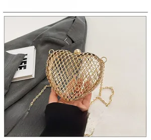 Macro detail of golden heart-shaped hollow metal evening bag with mesh weave texture