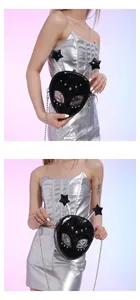 Detail of black alien-shaped crossbody bag with star antennas and holographic eyes