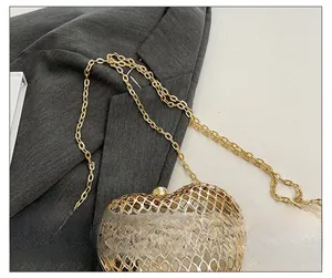 Detailed view of elegant gold heart-shaped metal evening bag with slim chain strap