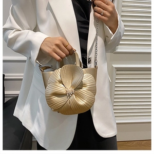 Detail of 3D floral petals on a champagne gold PU handbag with a metal chain strap