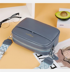 Detail of blue pebble leather camera bag with colorful geometric woven wide shoulder strap