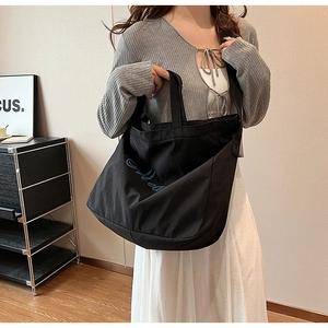 Vue détaillée d'un grand sac fourre-tout en toile noire avec broderie artistique bleue