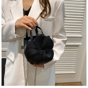 Detail of 3D pleated flower design and bead center on a black matte leather handbag