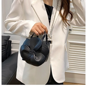 Detail of artistic 3D flower handbag in black leather with beaded center and silver chain