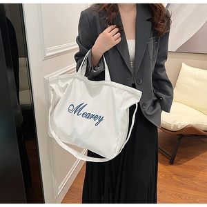Gros plan détaillé du sac cabas en toile blanche avec broderie Mearey bleue et poignées