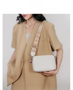 Creamy white leather crossbody camera bag with colorful geometric woven shoulder strap