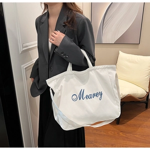 Sac cabas en toile blanche avec broderie Mearey bleue dans un décor intérieur cosy